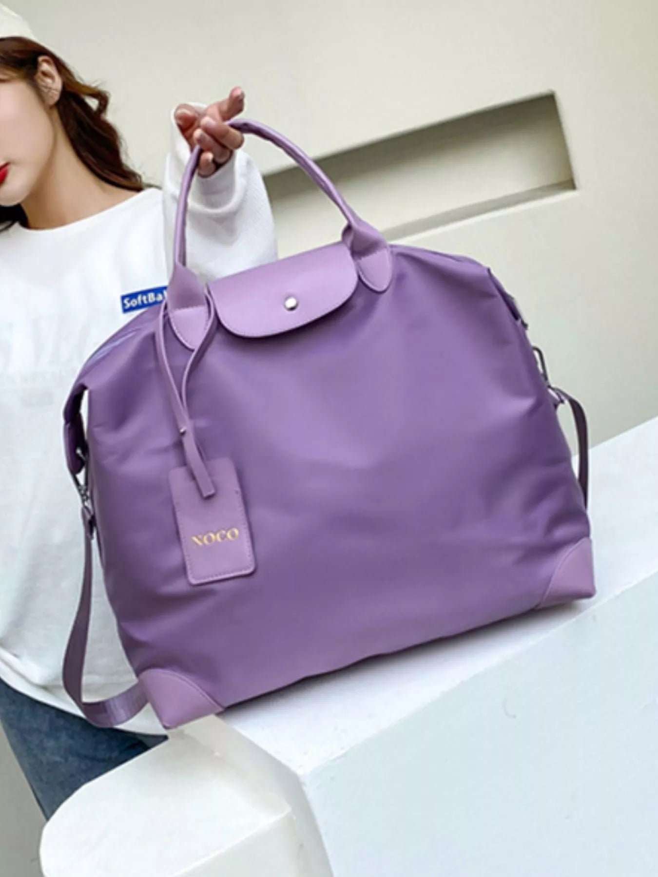 Purple handbag with visible brand name on a white surface