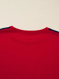 Close-up of a red shirt with navy trim on a beige background