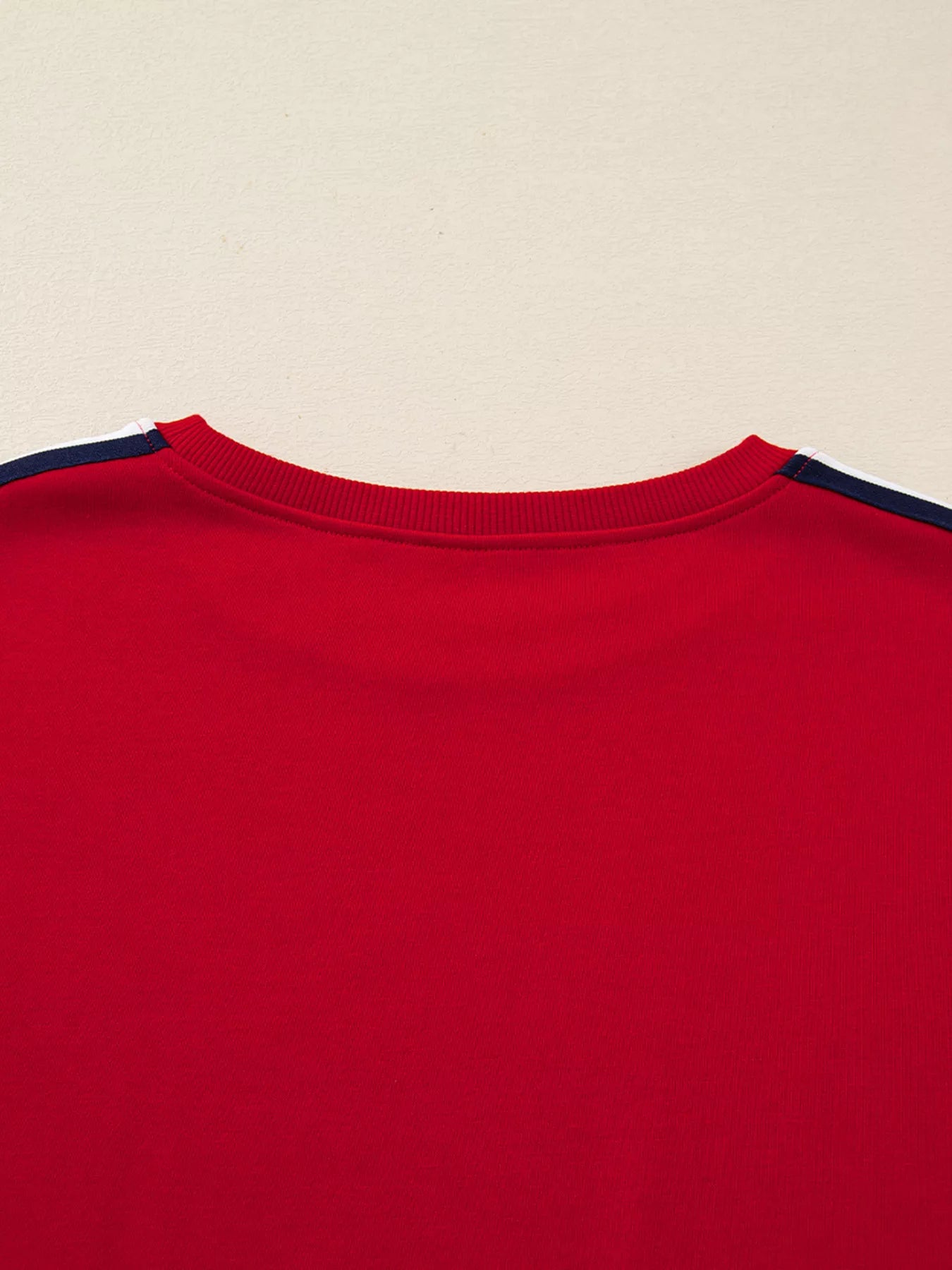 Close-up of a red shirt with navy trim on a beige background