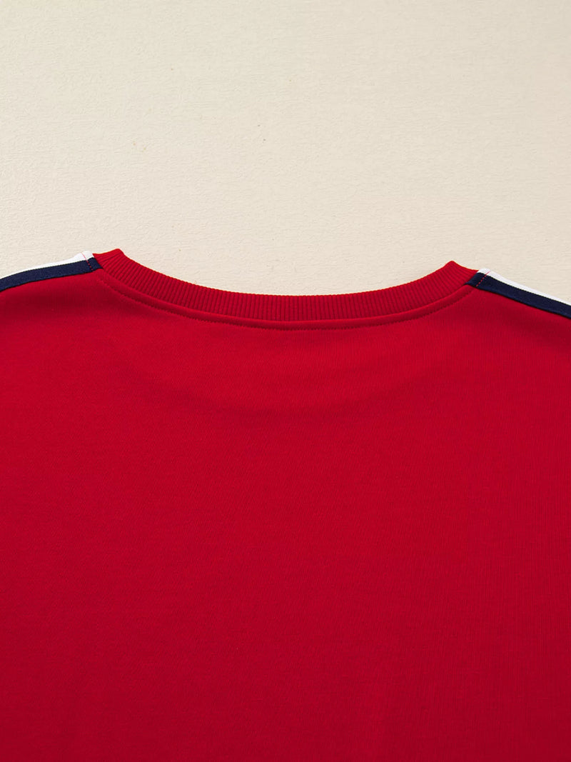 Close-up of a red shirt with navy trim on a beige background