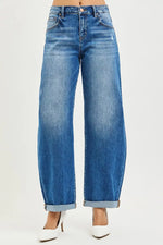 Blue jeans worn by a person on a white background with white high heels on