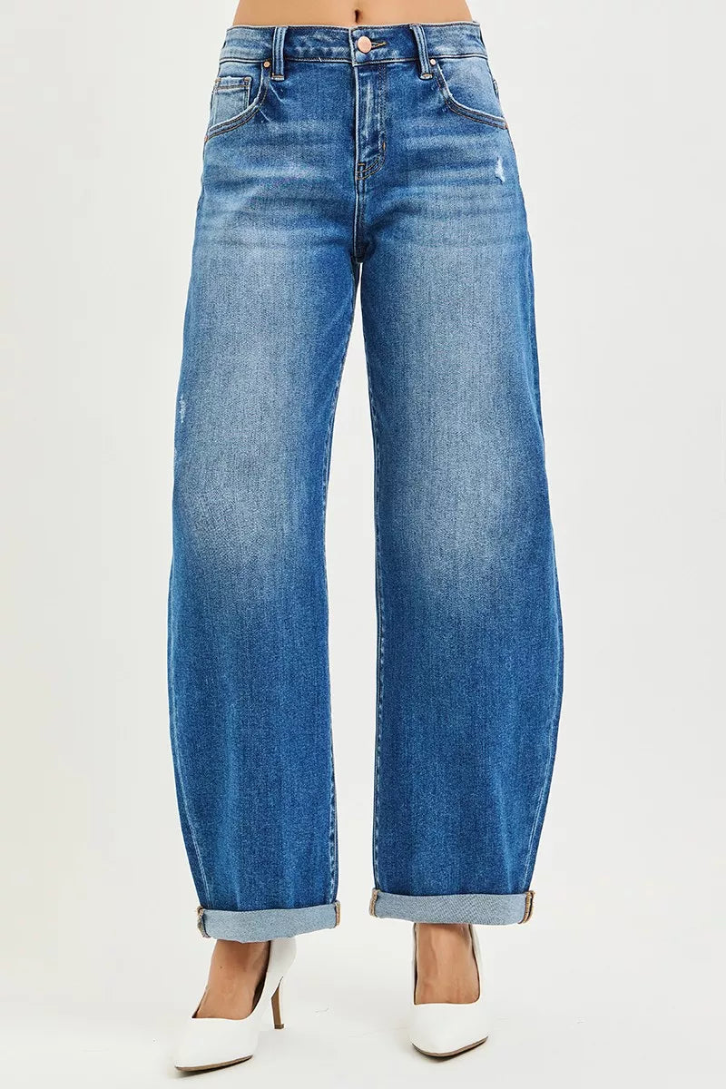Blue jeans worn by a person on a white background with white high heels on