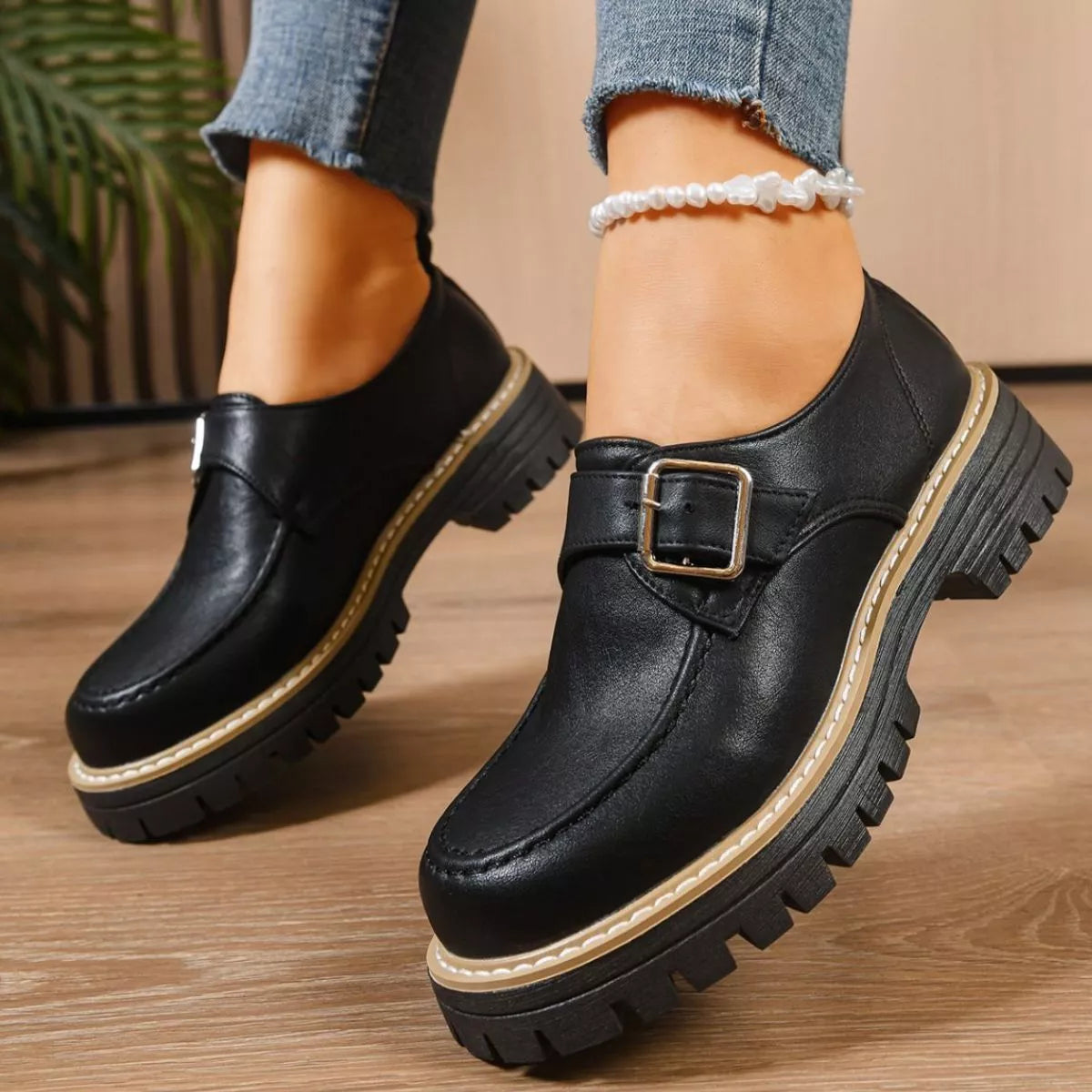 Black leather shoes with a buckle on a wooden floor