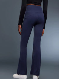 Person wearing navy flared pants and a black long-sleeve top on a gray background