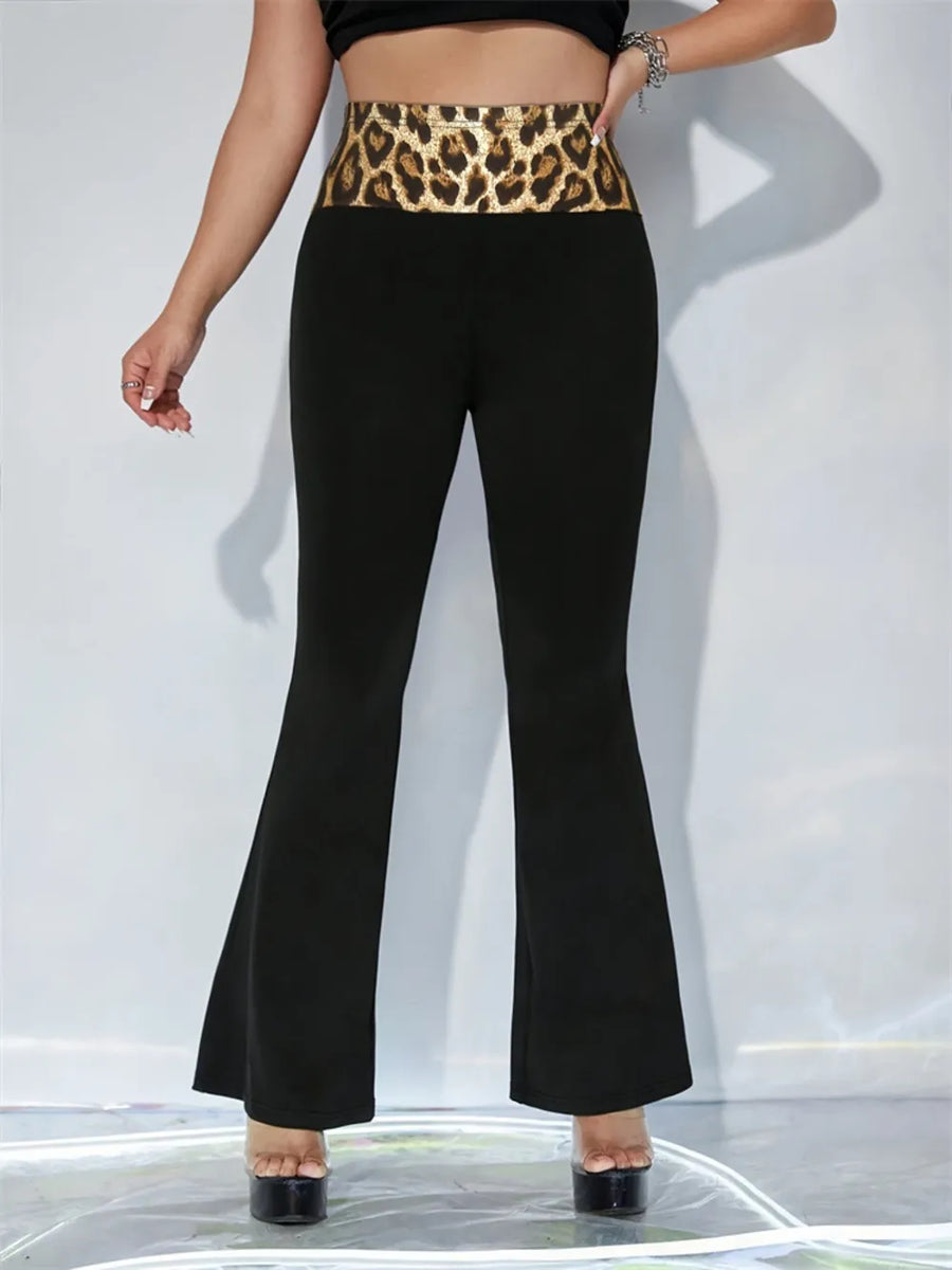 Person wearing black flared pants with a leopard print waistband on a white background