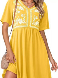 Yellow dress with white floral embroidery on a white background