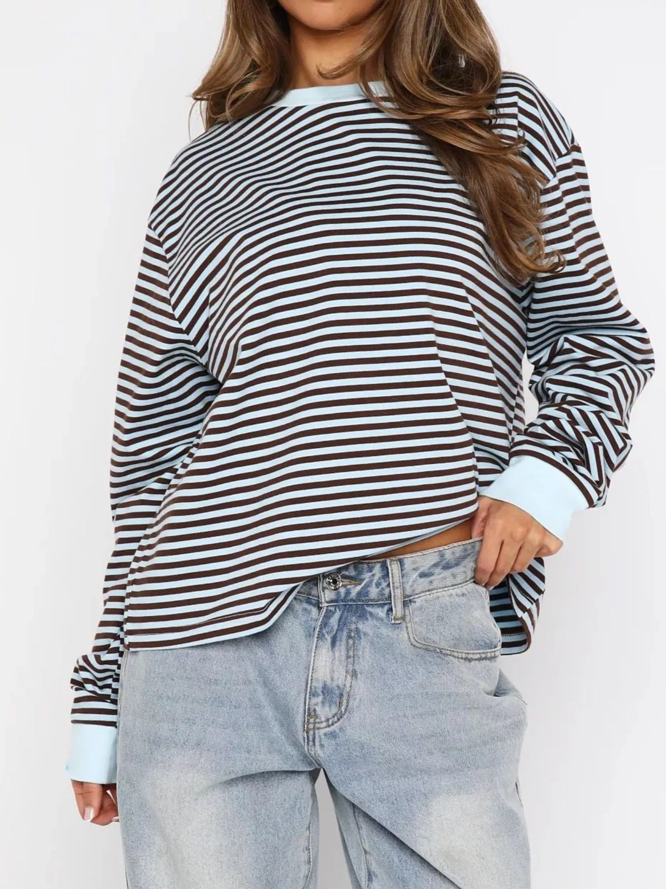 Person wearing a striped long-sleeve shirt and light blue jeans on a white background