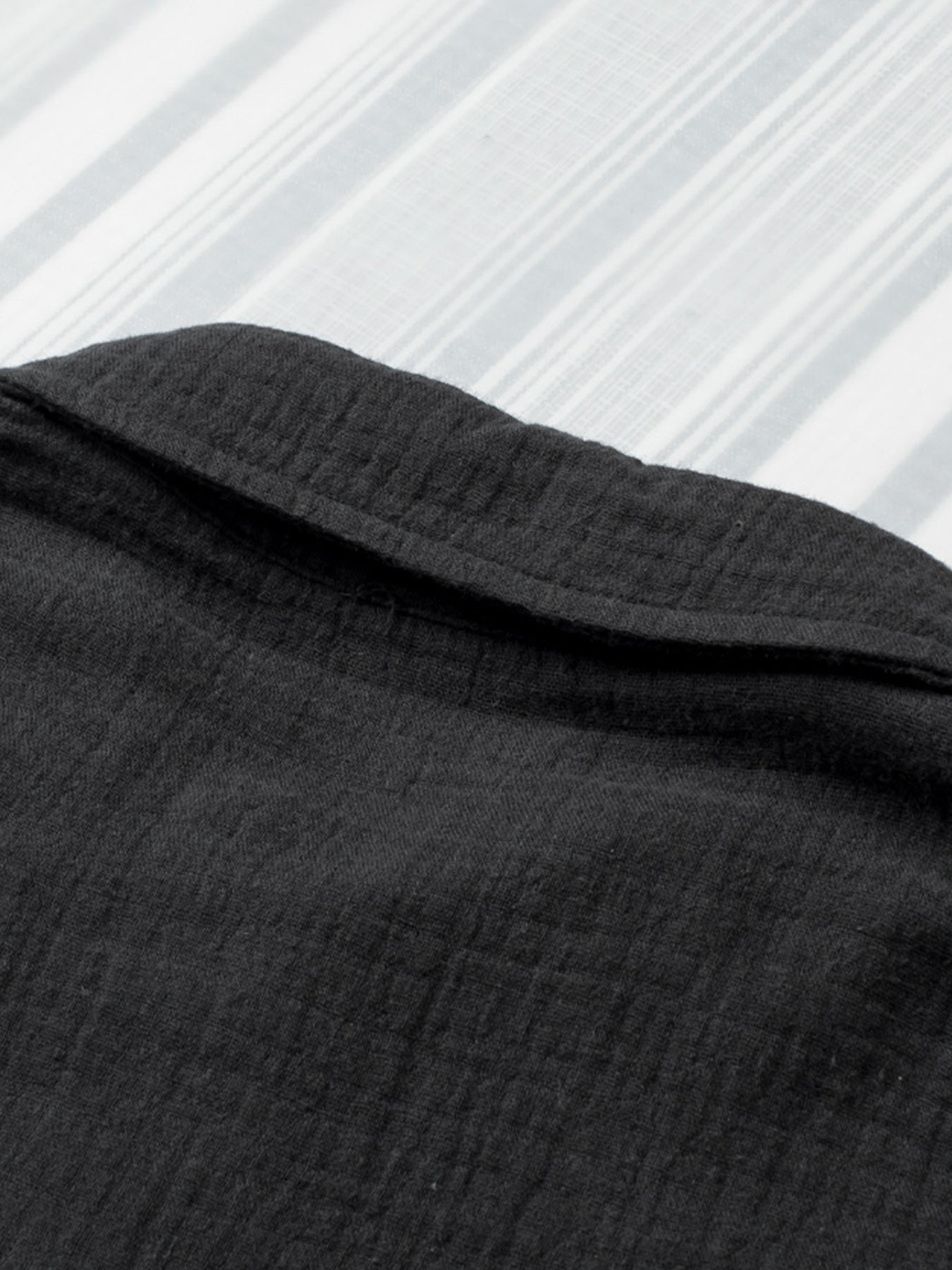 Close-up of black fabric with a textured pattern on a white background