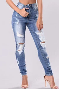 Distressed blue jeans worn by a person on a light gray background