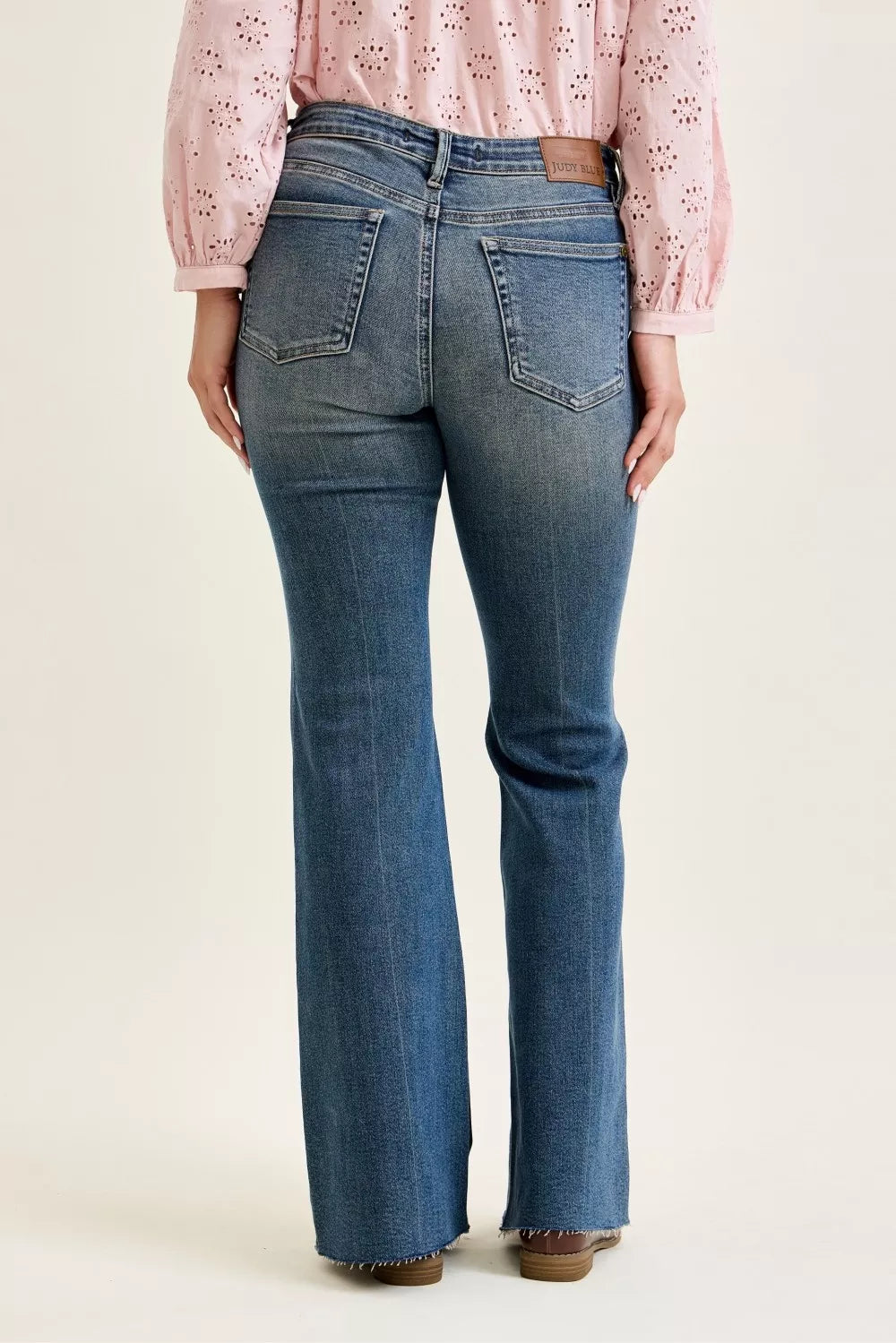 Person wearing blue jeans and a pink blouse on a white background