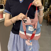 Person holding a small checkered bag with a phone case attached, in an indoor setting.