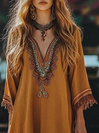 Mustard yellow dress with intricate beading and fringes, worn by a model with long hair.