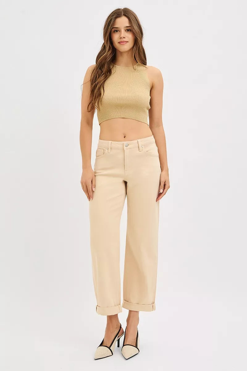 Woman wearing a beige sleeveless top and pants on a white background