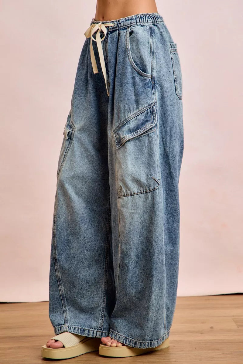 Wide-leg jeans with a drawstring waist on a wooden floor.