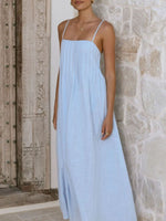 Woman wearing a light blue dress against a stone wall.