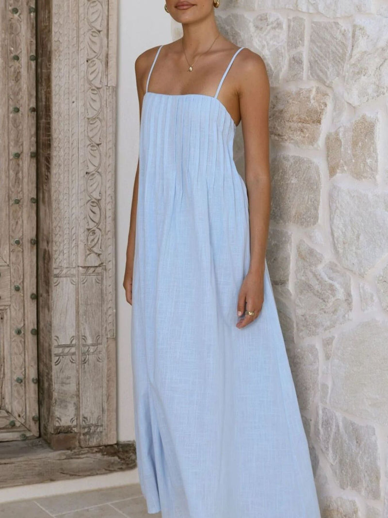 Woman wearing a light blue dress against a stone wall.