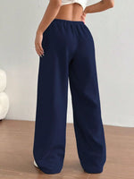 Navy blue wide-leg pants worn by a person on a light wooden floor.