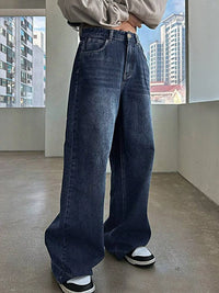 Person wearing blue jeans standing indoors with a cityscape in the background