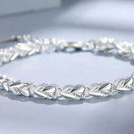 Silver bracelet with leaf-like design on a light gray background