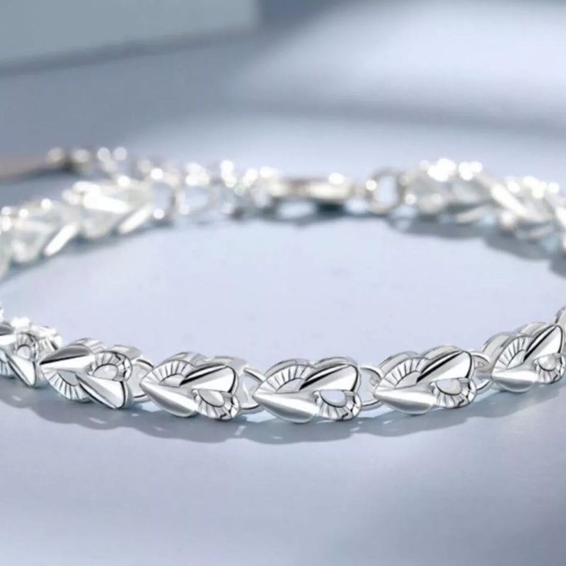 Silver bracelet with leaf-like design on a light gray background
