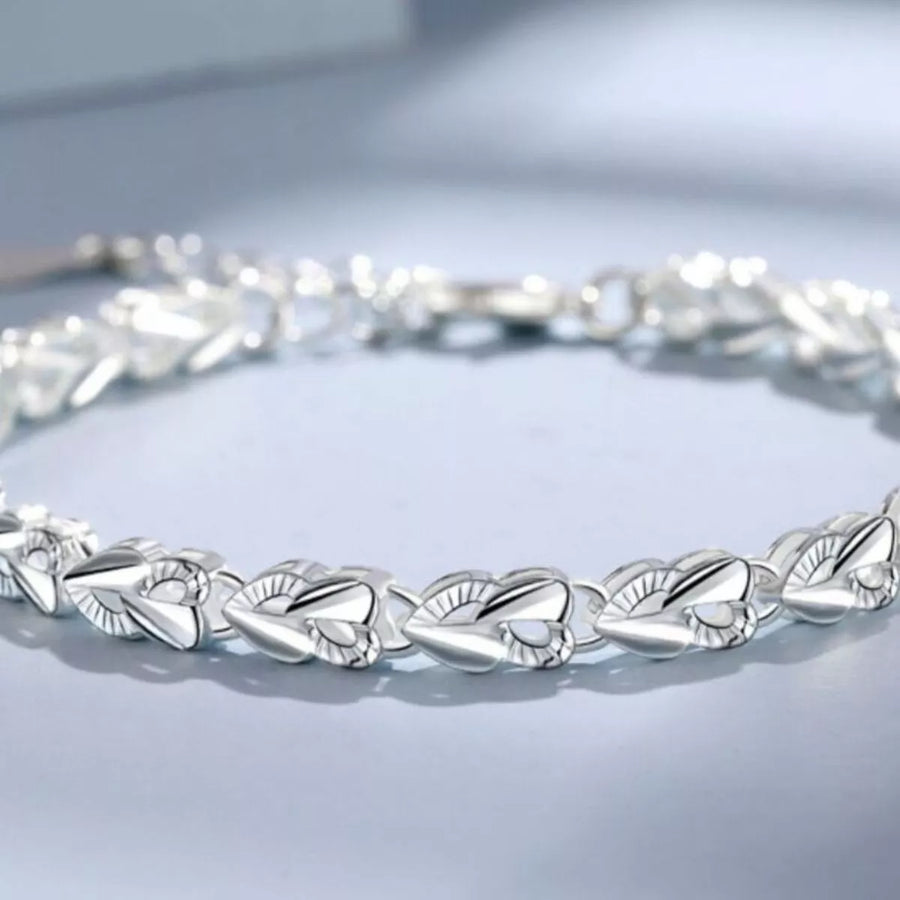 Silver bracelet with leaf-like design on a light gray background