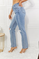 Person wearing light blue distressed jeans in a minimalistic setting