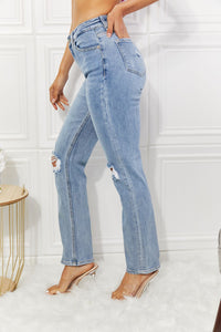 Person wearing light blue distressed jeans in a minimalistic setting