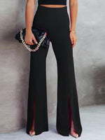 Person wearing black high-waisted pants with a slit, holding a black clutch with gold chain.