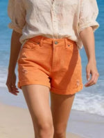 Person wearing orange shorts and a light-colored shirt on a beach.