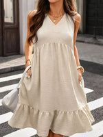 Woman wearing a beige sleeveless dress crossing a street.