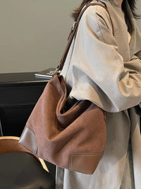 Person holding a brown handbag with a neutral background