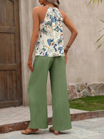 Woman wearing a floral top and green pants standing outdoors.