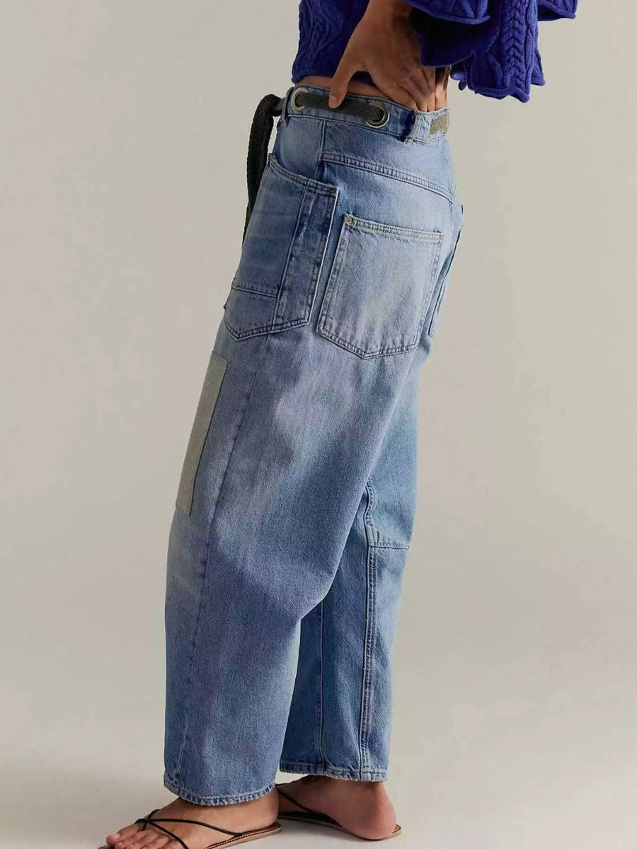 Person wearing light blue jeans and a purple top on a plain background