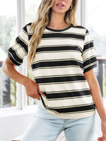 Woman wearing a black and white striped shirt with light blue jeans indoors.