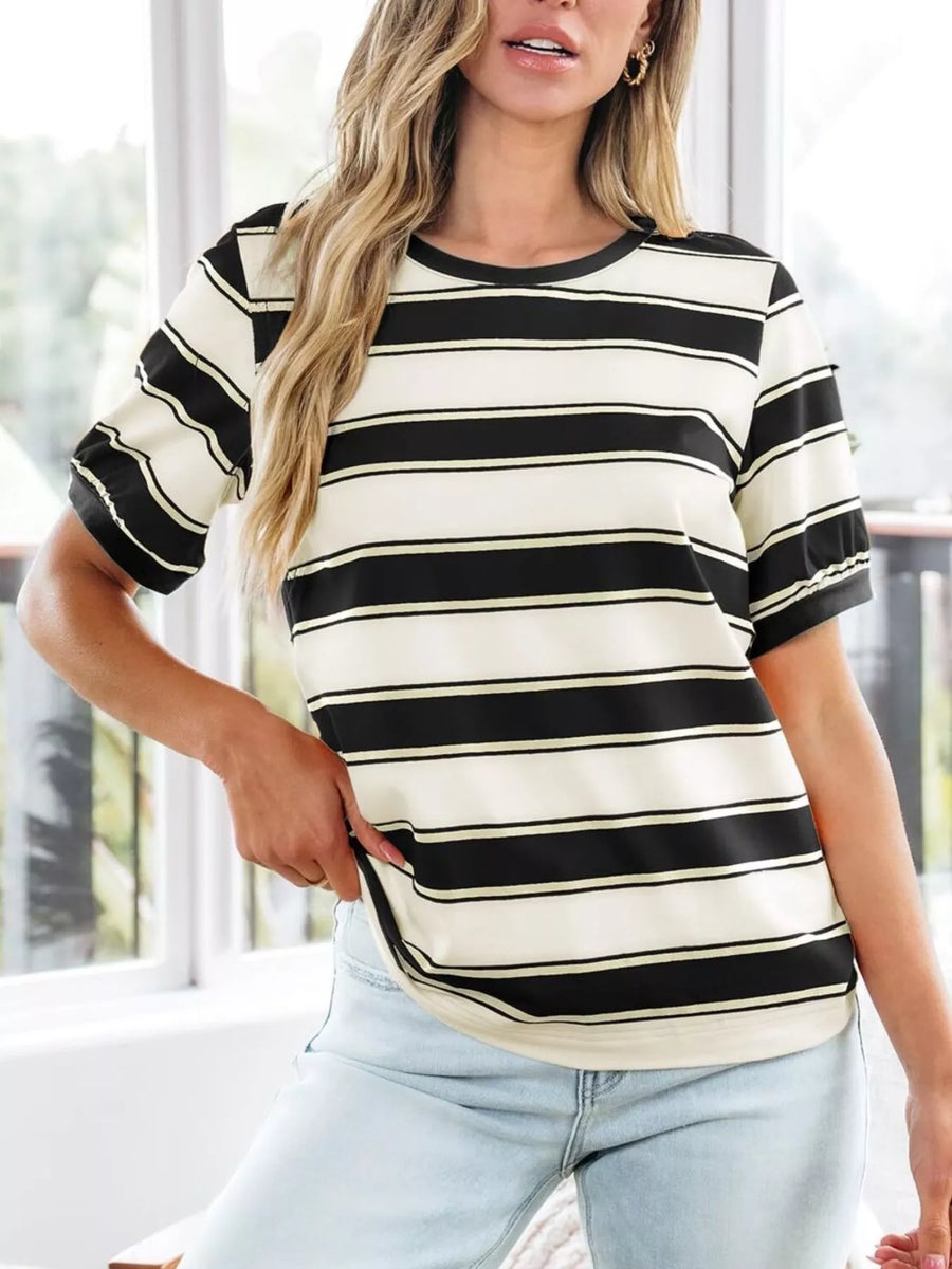 Woman wearing a black and white striped shirt with light blue jeans indoors.