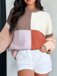 Person wearing a color-blocked sweater with a neutral background