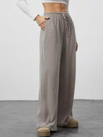 Person wearing gray ribbed wide-leg pants on a plain background