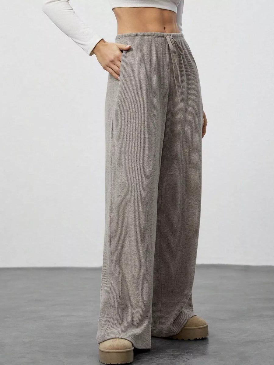 Person wearing gray ribbed wide-leg pants on a plain background