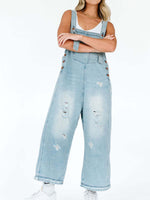 Person wearing light blue denim overalls on a white background
