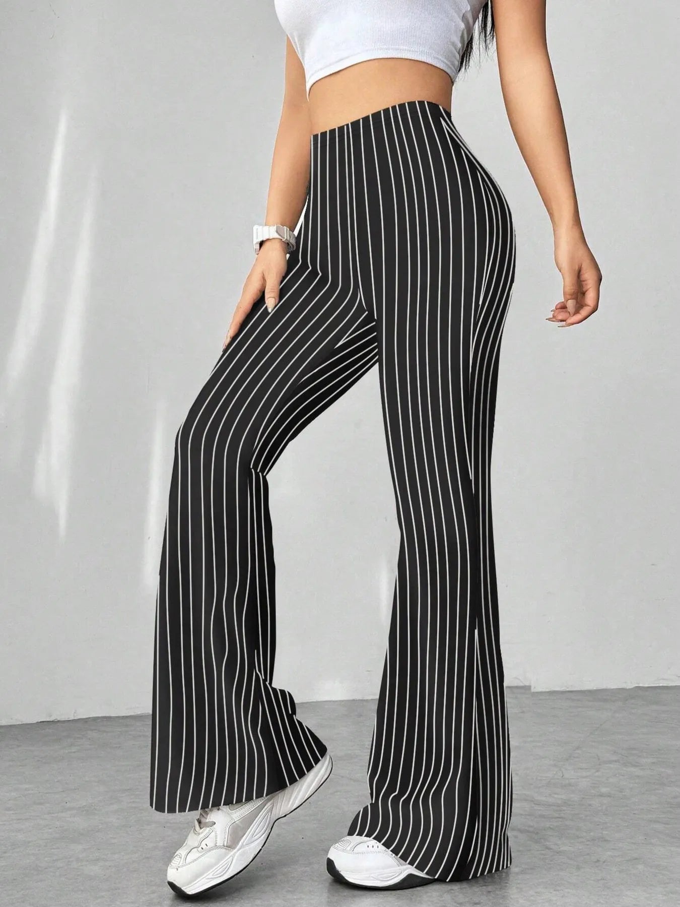 Person wearing black and white striped pants with a plain background
