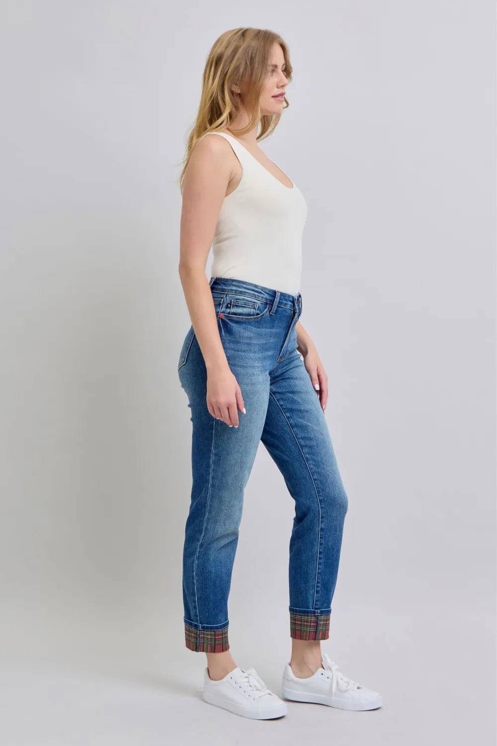Woman wearing blue jeans and a white top on a plain background