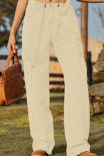 Person wearing beige cargo pants holding a brown leather bag outdoors.