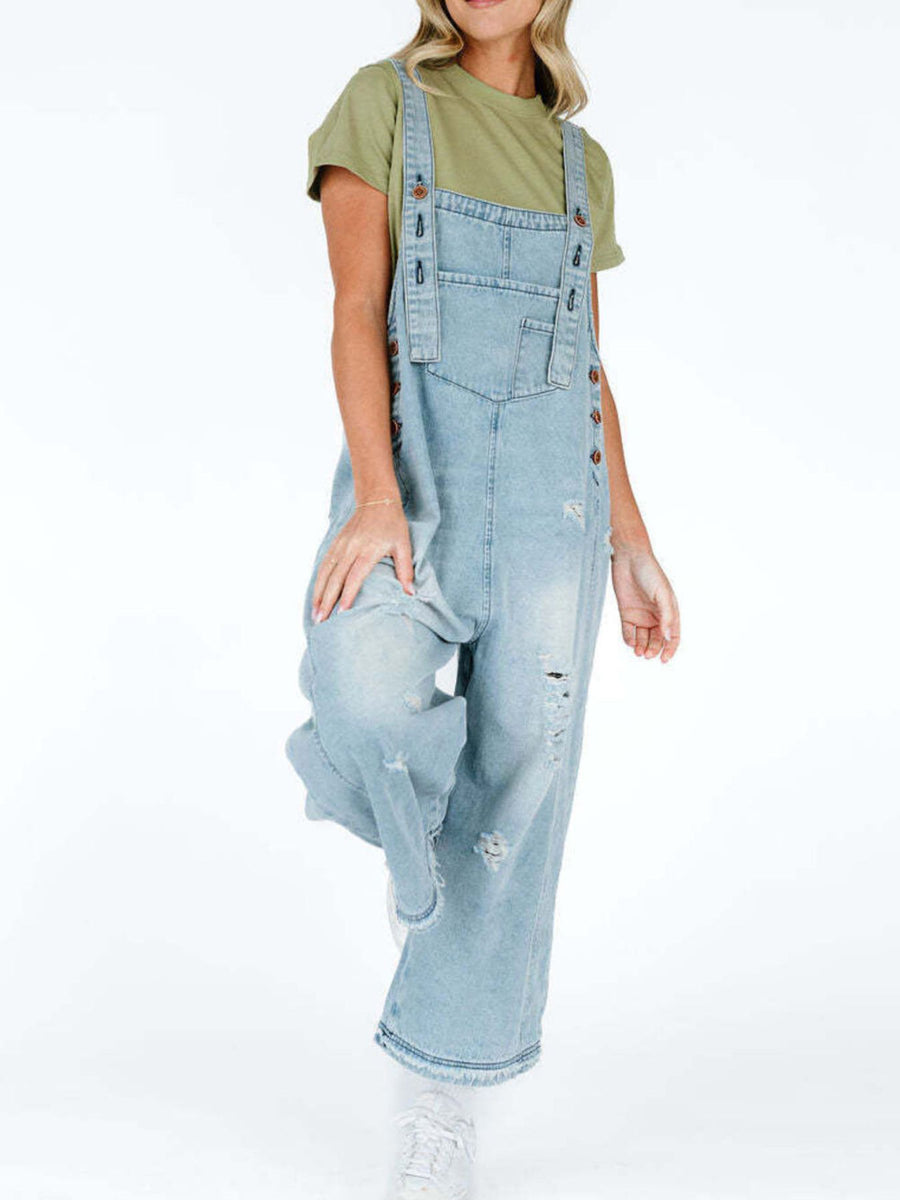 Person wearing light blue denim overalls on a white background