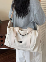 Person holding a beige handbag with a visible brand logo.