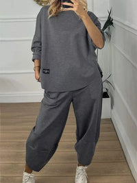 Person wearing a gray tracksuit in a minimal indoor setting