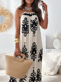 Woman wearing a white dress with black patterns, holding a straw bag in a home setting.