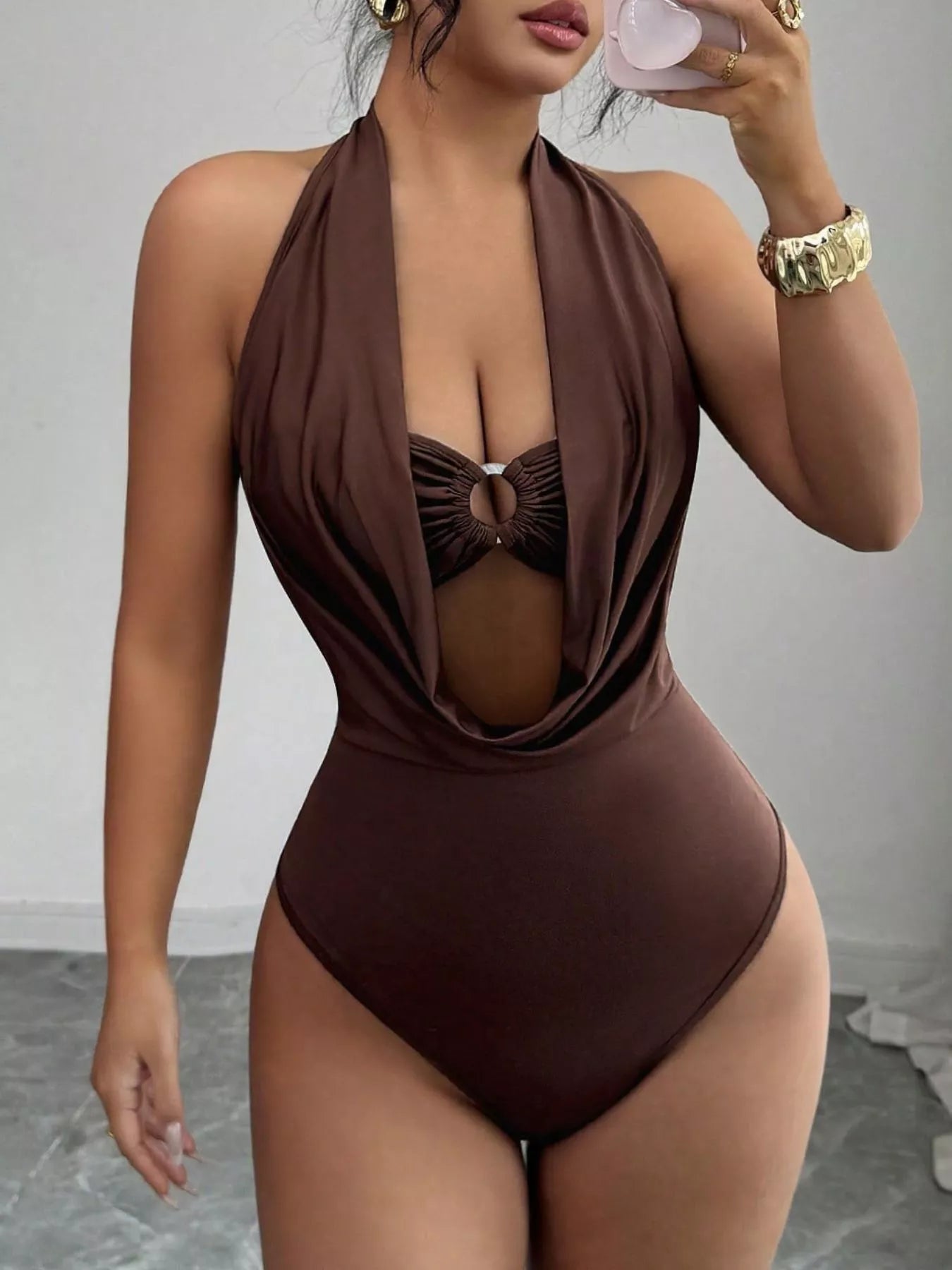Woman wearing a brown halter neck swimsuit against a neutral background