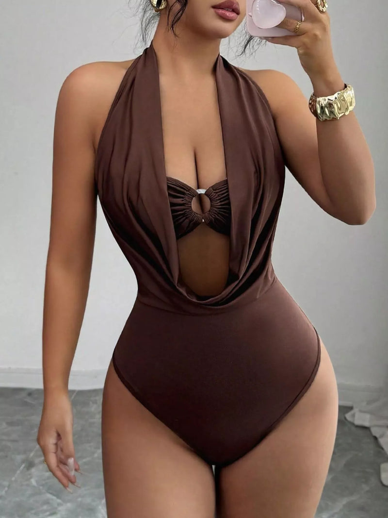 Woman wearing a brown halter neck swimsuit against a neutral background