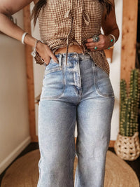 Person wearing a checkered top and blue jeans indoors.