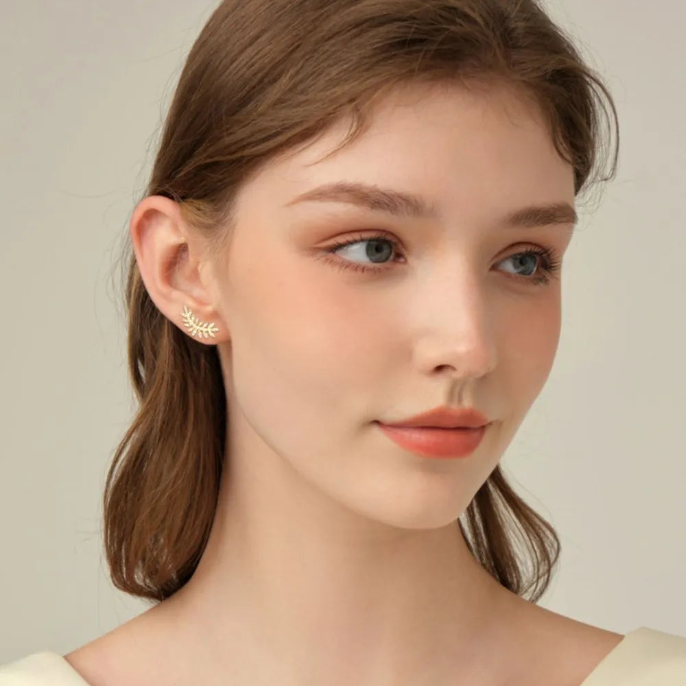Close-up of a woman wearing a delicate earring against a neutral background